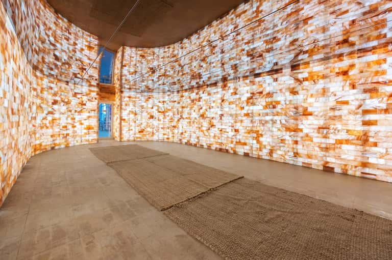 Modern spa sauna interior with orange and white tile walls and wooden benches