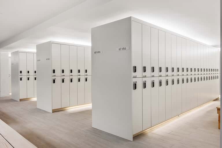 Modern white locker room with numbered storage units and natural lighting