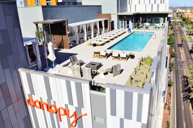 Rooftop pool deck at Canopy hotel with lounge chairs, fire pit, and city skyline views