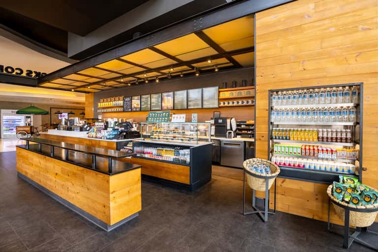 Casual beach café with wooden counter, menu boards, and refrigerated beverage displays