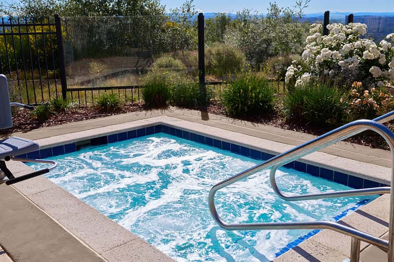Hot tub on scenic patio with flowering plants and canyon landscape views