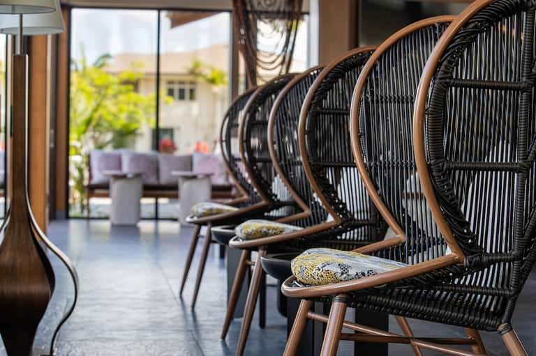 Woven rattan chairs in beige and black arranged in resort lounge with ocean views