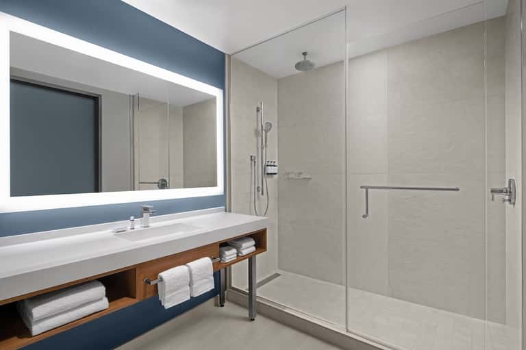 Modern bathroom with illuminated mirror, floating vanity, and rainfall shower