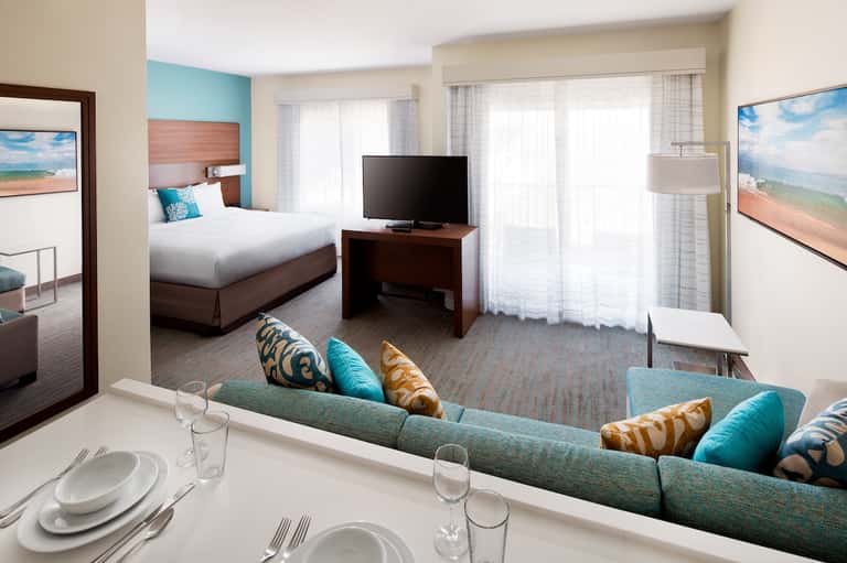 Spacious hotel suite with separate bedroom, living area, turquoise accents, and oceanview balcony