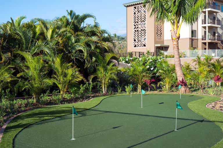 Mini golf course with lush tropical landscaping, palm trees, and resort building exterior