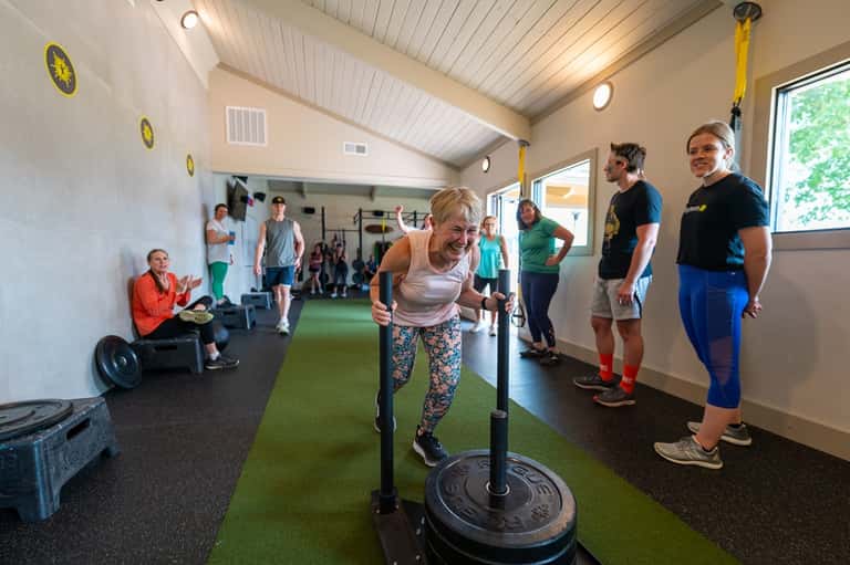 Group fitness class with instructor leading participants through barbell workout in bright gym space
