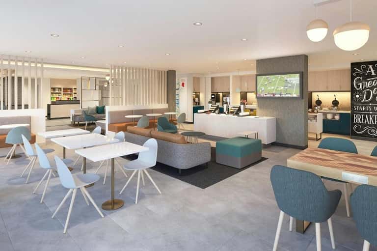 Modern hotel lobby lounge with seating areas, kitchen, and contemporary decor