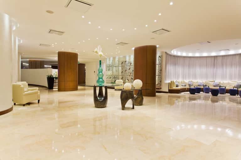 Elegant hotel lobby with polished marble floors, wooden columns, and contemporary furnishings