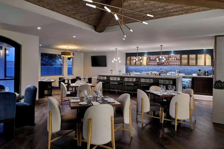 Upscale dining room with elegant table settings, bar area, and panoramic evening window views