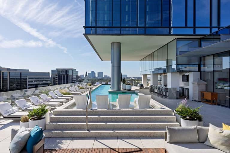 Urban rooftop pool with city skyline views, loungers, and modern architectural design