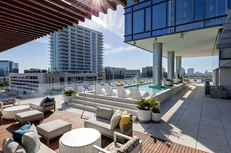 Rooftop pool deck with lounge chairs, city skyline views, and modern canopy