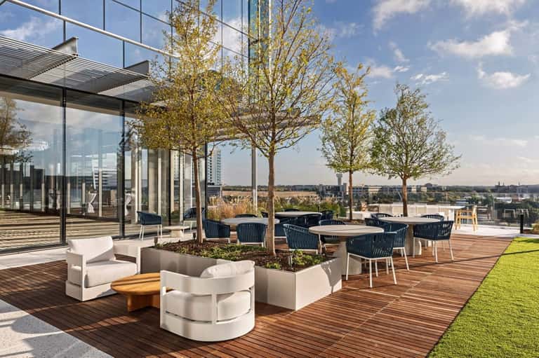 Rooftop terrace with modern lounge seating, trees, and panoramic city skyline views