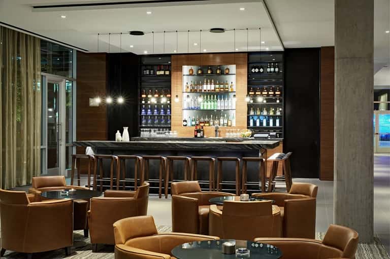 Contemporary bar lounge with backlit shelving displaying spirits, leather seating, and modern design