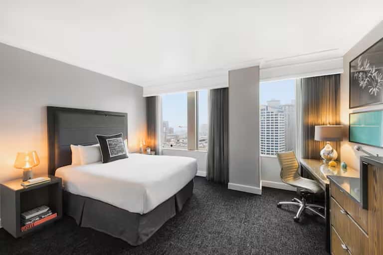 Upscale hotel room with city view, modern furnishings, and work desk