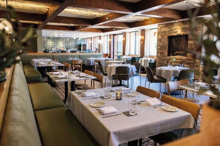 Upscale restaurant dining room with white tablecloths and stone fireplace accent