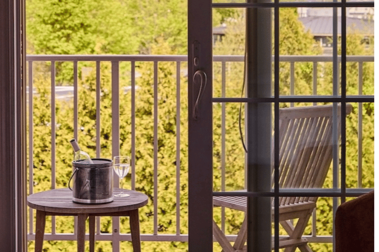 Private balcony view through French doors overlooking forested landscape and vineyards