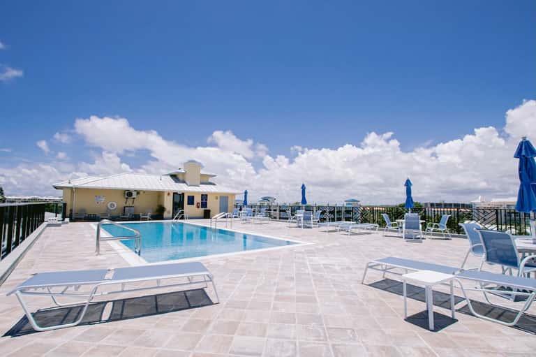 Rooftop pool deck with lounge chairs, umbrellas, and clear sky view