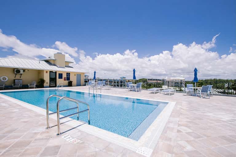Rooftop swimming pool with white loungers and city waterfront views at dusk