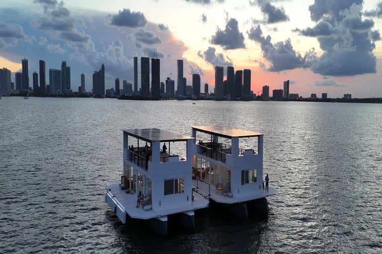 Floating luxury villa with white modern architecture overlooking Miami skyline at dusk