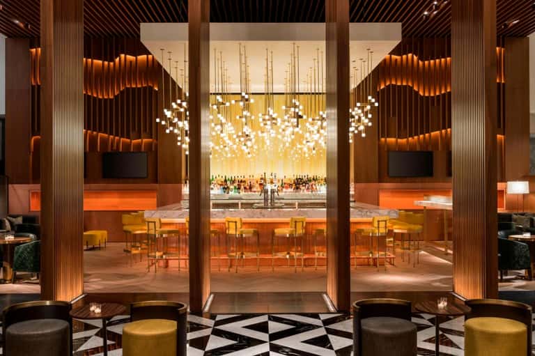 Luxury bar lounge with cascading white pendant lights, wood paneling, and modern design
