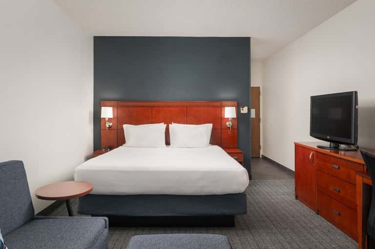 Hotel bedroom with orange headboard, white bedding, TV, and contemporary furnishings