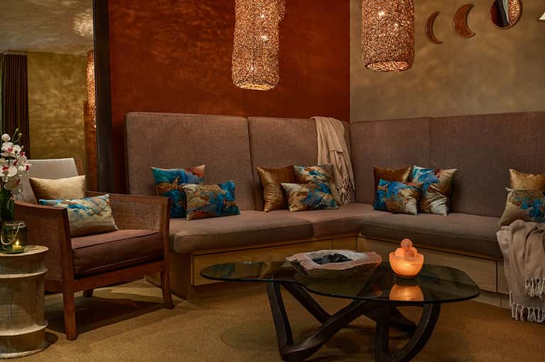 Upscale lounge with taupe sectional sofa, decorative pillows, and warm ambient lighting