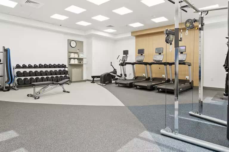 Fitness center with treadmills, dumbbells, wall mirror, and exercise equipment