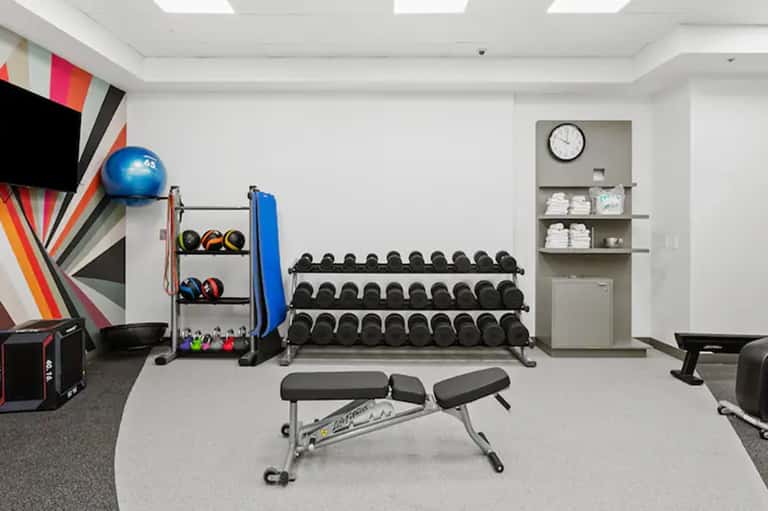 Modern hotel fitness center with dumbbells, medicine balls, gym equipment, and colorful wall art