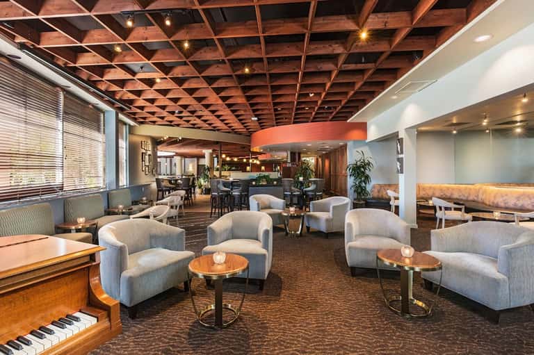 Elegant hotel lobby lounge with wooden ceiling, piano, comfortable seating, and modern decor