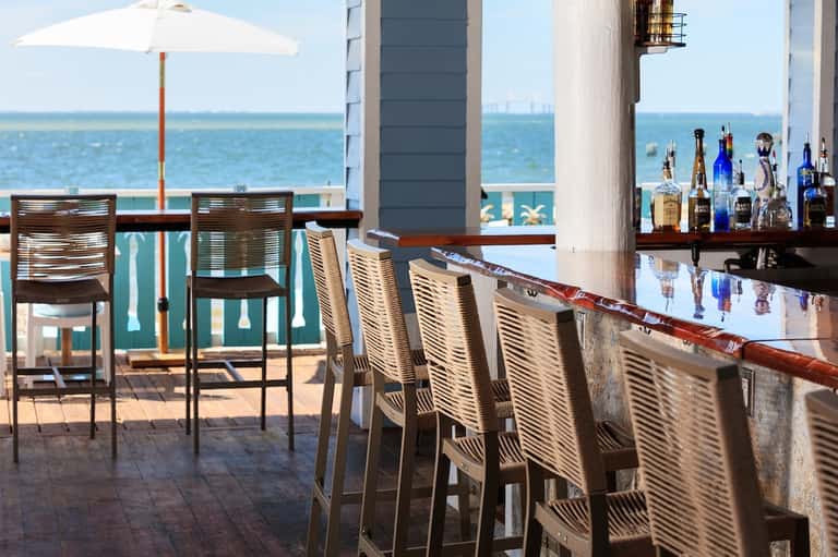 Oceanfront bar with high seating, bottles display, ocean views, and umbrella