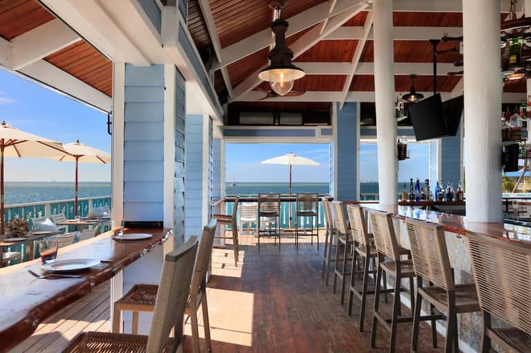 Oceanview restaurant with white columns, wooden deck, bar seating, and ocean horizons