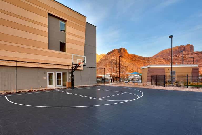Outdoor basketball court next to modern building with desert mountains in background
