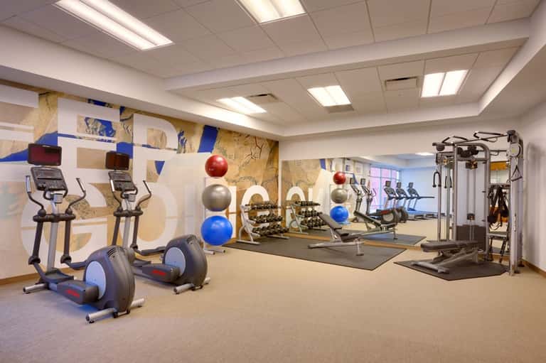 Fitness studio with cardio equipment, dumbbells, exercise balls, and motivational wall art