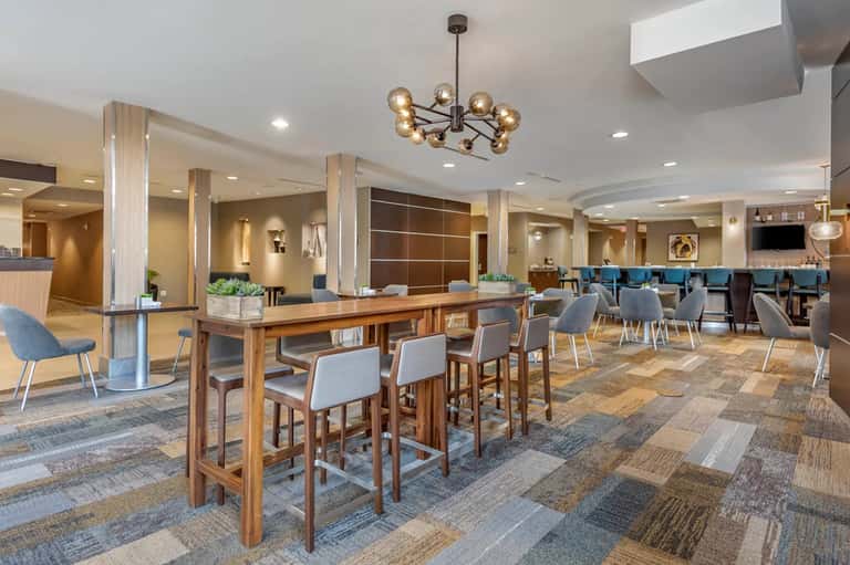 Hotel lobby and bar area with wooden pillars, patterned flooring, modern furnishings, and contemporary design