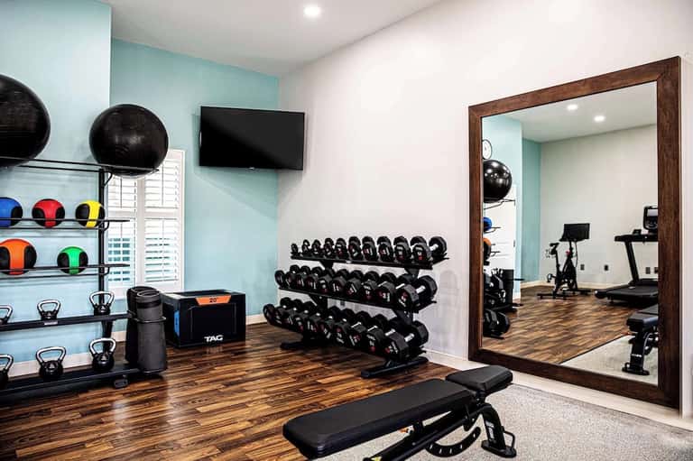 Modern fitness center with dumbbell rack, exercise bikes, black medicine balls, and large mirror
