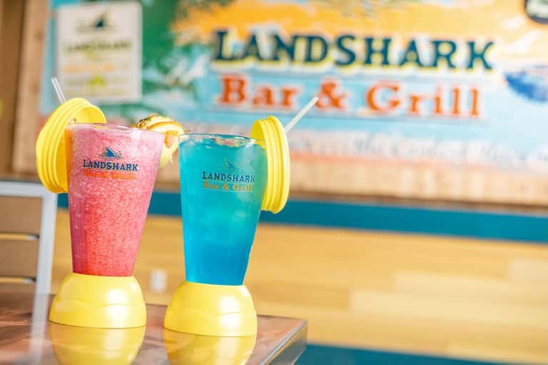 Two colorful tropical cocktails with yellow drink holders at Landshark Bar & Grill
