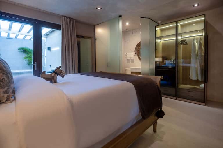 Modern hotel bedroom with king bed, ensuite bathroom, and patio access
