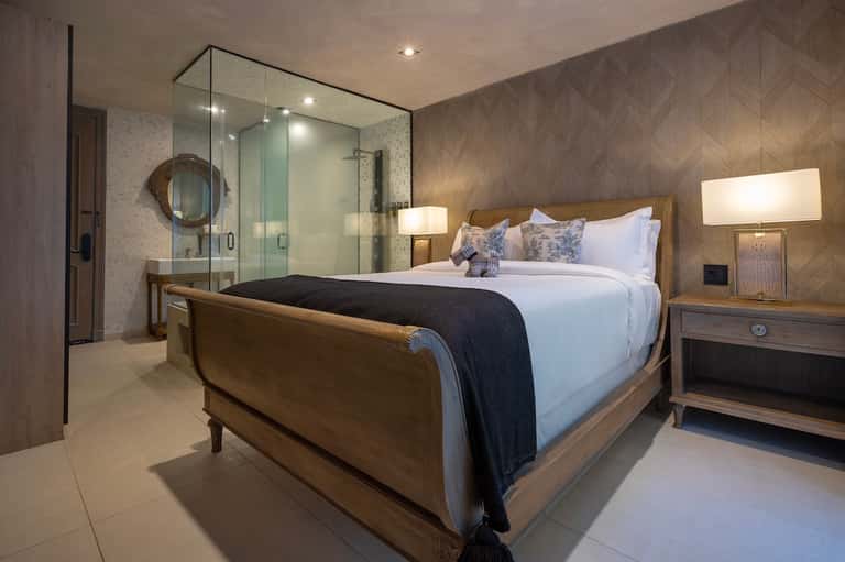 Luxury master bedroom with ensuite bathroom featuring spa shower and wooden platform bed