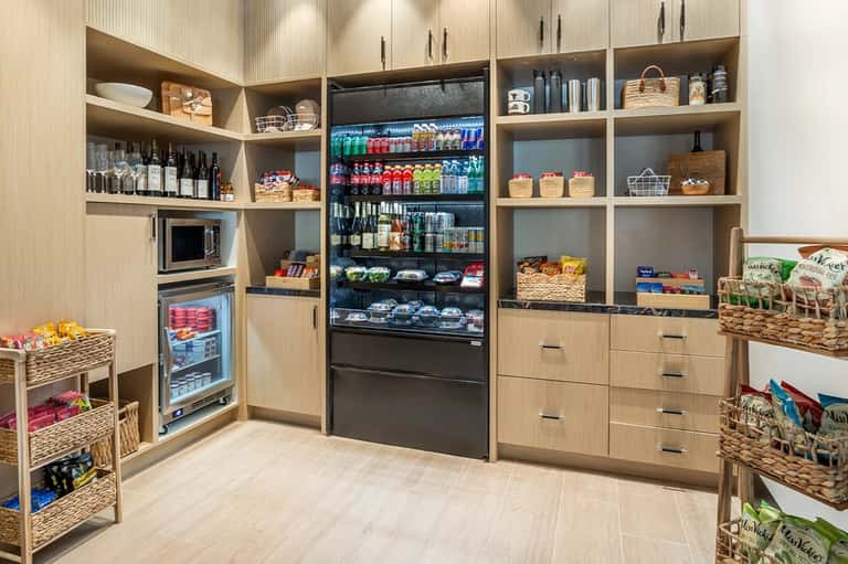 Market-style pantry with wood shelving, refrigerated beverage display, and organized snack baskets