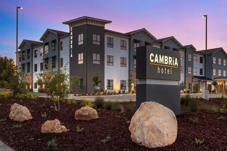 Contemporary Cambria Hotel exterior at dusk with modern architecture and decorative landscaping boulders