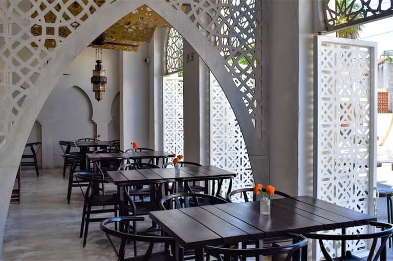 Mediterranean-style restaurant with white geometric screens, black furniture, and arched architecture