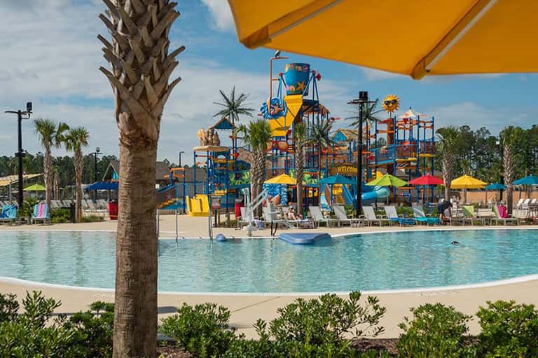 Colorful water park with blue and yellow playground, wave pool, and palm trees
