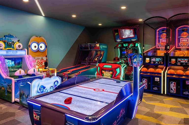 Game room with arcade machines, air hockey table, and colorful gaming equipment