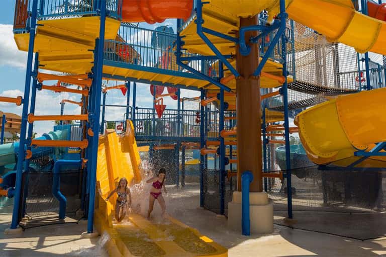 Water park with yellow slides and blue metal structures, children enjoying splash areas