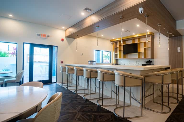Modern hotel lobby bar with wooden accents, blue doors, and dining area