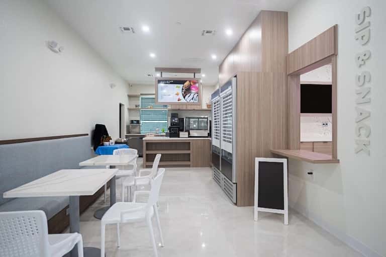 Modern casual dining area with white furniture, wooden cabinetry, and open kitchen concept