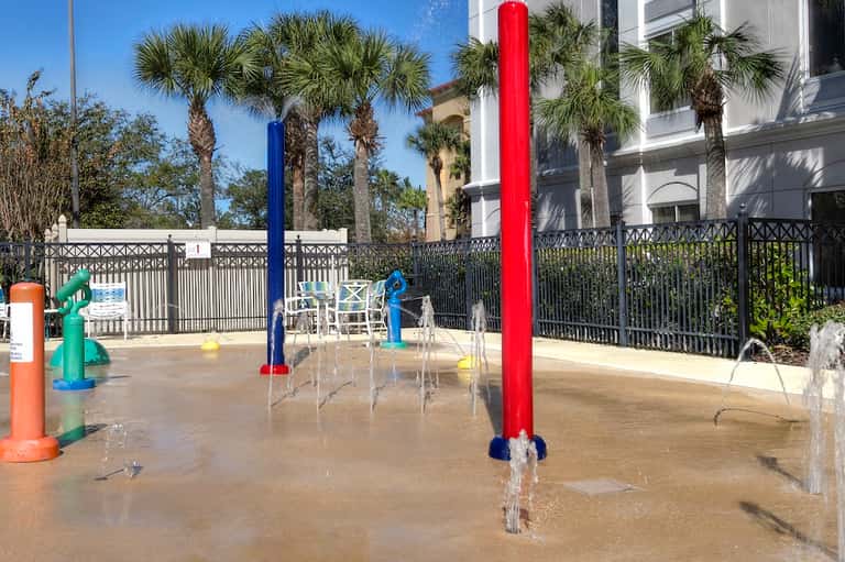 Resort splash pad for children with colorful water jets, fountains, and fencing