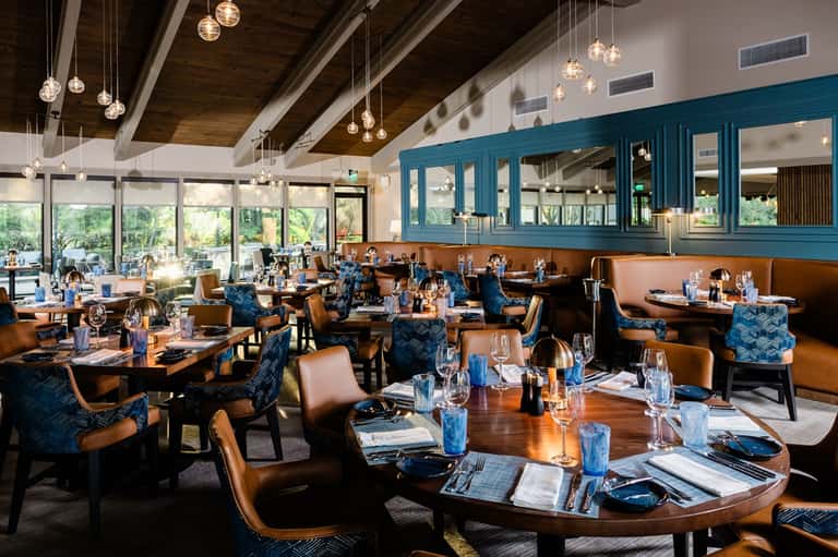 Upscale dining room with teal cabinets, leather seating, and large windows overlooking grounds