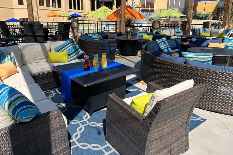 Waterfront patio lounge with navy furniture, striped cushions, colorful umbrellas, and ocean view