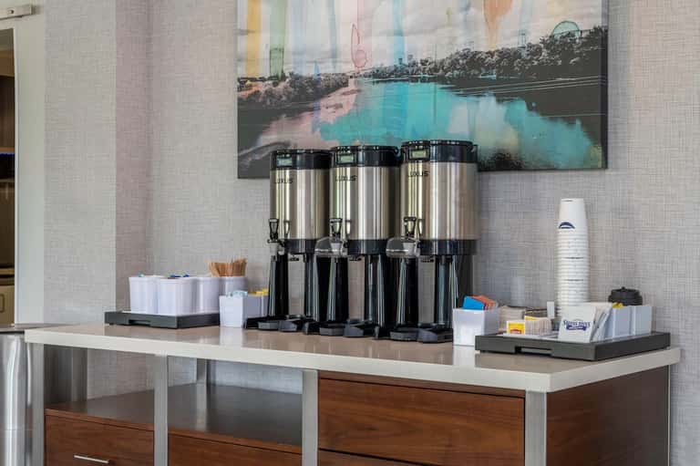 Coffee station with three thermal dispensers and hospitality supplies on counter